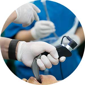 AA person in scrubs inserts a video laryngoscope on a patient 