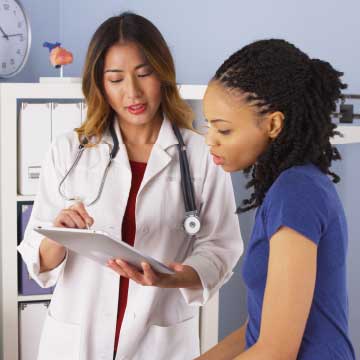 A woman in a white lab coat talks to a patient