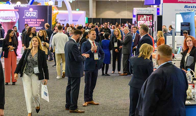 Several people standing and walking inside an exhibit hall in a convention center