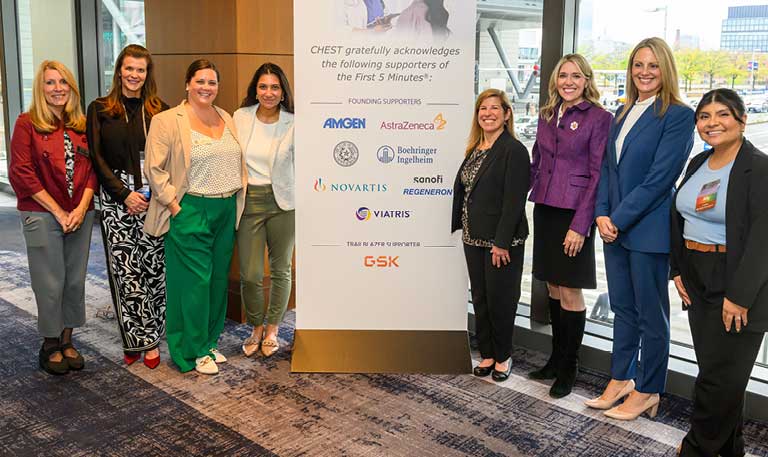 A group of people smiling and standing on either side of a floor sign